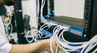 IT technician managing cabling in a data center to prevent risks from inaccurate and incomplete inventory documentation.